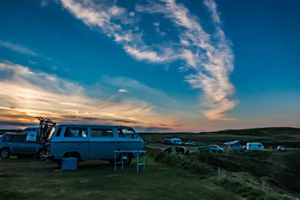 Sonnenuntergang auf einem Campingplatz mit vielen Fahrzeugen, die sich den Platz teilen.
