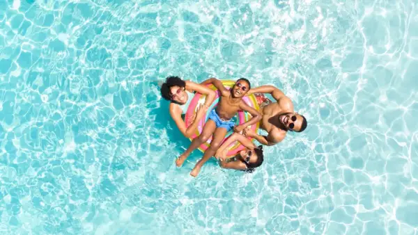 Glückliche Familie treibt auf einem bunten Schwimmring im Pool. Perfekt für die packliste schwimmbad: Badesachen, Sonnenbrillen und gute Laune!