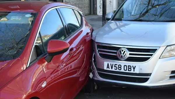 Mein parkendes Auto wurde angefahren. Ein rotes Auto ist seitlich gegen einen silbernen VW gestoßen.