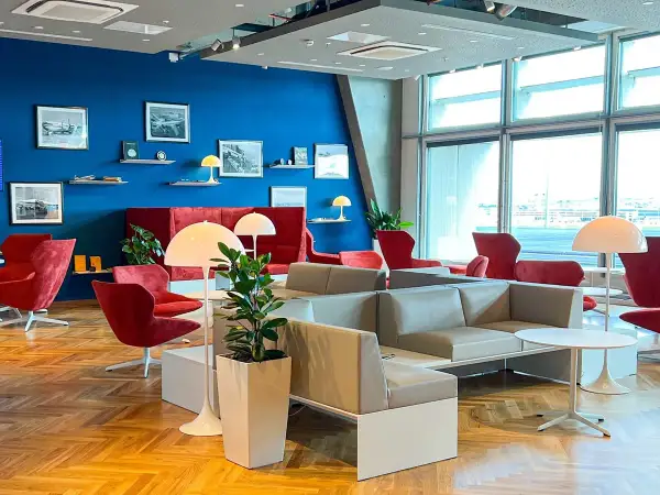 Gemütliche Lounge mit roten Sesseln und grauen Sofas, ideal für Reisende mit Priority Pass Stuttgart.
