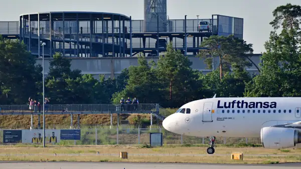 Lufthansa Airbus A320-200 auf dem Rollfeld in Frankfurt. Im Hintergrund ein Parkhaus und Bäume.