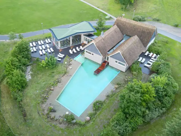 Beech Resort Plauer See: Einladender Poolbereich mit Liegen und moderner Architektur, umgeben von Grün.