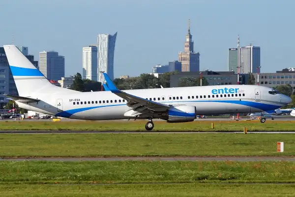 Ein Enter Air Flugzeug rollt auf dem Rollfeld, die Skyline von Warschau im Hintergrund.