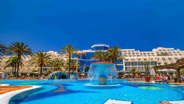 Einladender Poolbereich mit Wasserrutsche und Palmen vor dem Costa Calma Palace Hotel.