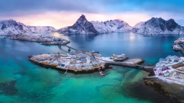 Winterliche Lofoten: Ein Traum für jeden Skandinavien Urlaub. Schneebedeckte Berge, türkisfarbenes Wasser und malerische Fischerdörfer.