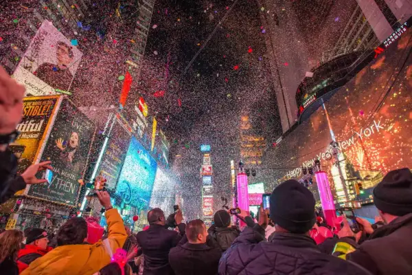 Konfetti regnet auf die Menge am Times Square. Ein Feuerwerk erhellt den Himmel, während die Menschen den Jahreswechsel feiern. Silvester in New York ist ein unvergessliches Erlebnis.