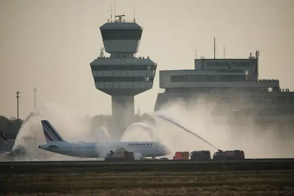 Air France Flugzeug wird auf dem Rollfeld der Berlin Airports mit Wasser begrüßt. Der Kontrollturm und das Terminal sind im Hintergrund zu sehen.