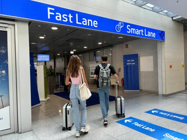 Paar geht zur flughafen sicherheitskontrolle. Ein Schild weist auf die "Fast Lane" und "Smart Lane" hin.