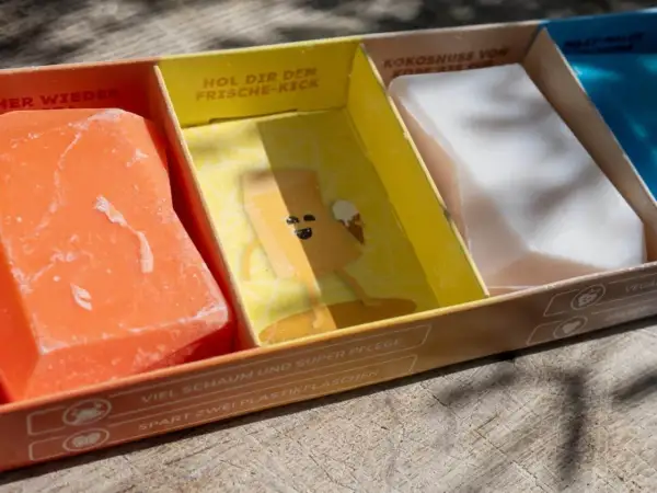 Erste Eindrücke von Duschbrocken: Ein orangefarbener, ein gelber mit Comic und ein weißer festes Shampoo. Umweltfreundlich & pflegend.