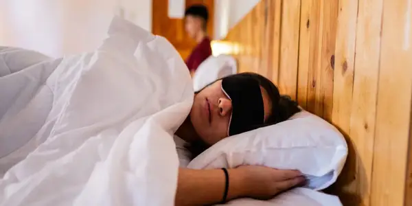 Frau schläft mit Schlafmaske, um Jetlag zu bekämpfen. Die Richtung des Jetlags ist egal, Hauptsache Schlaf.