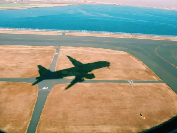 Schatten eines Flugzeugs auf dem Rollfeld. Gute tipps langstreckenflug: entspannt bleiben, Wasser trinken, bewegen.