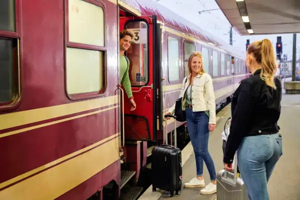Junge Leute mit Gepäck steigen in den Zug für ihre TUI Bahnreise.