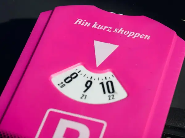 Pink parkschein mit der Aufschrift "Bin kurz shoppen". Die Parkscheibe ist auf 9 Uhr eingestellt.