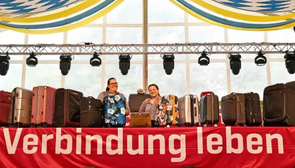 Zwei Frauen präsentieren eine Auswahl an Koffern für eine Auktion. Die Koffer sind in verschiedenen Farben und Mustern erhältlich.