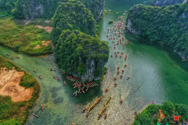 Boote auf einem grünen Fluss in Ninh Binh, umgeben von üppigen, felsigen Inseln.