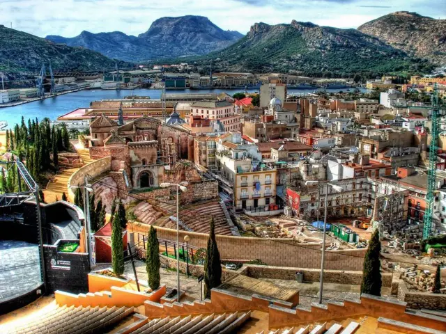 Blick über die Stadt Cartagena, Spanien, mit Hafen, historischen Gebäuden und Bergen im Hintergrund.
